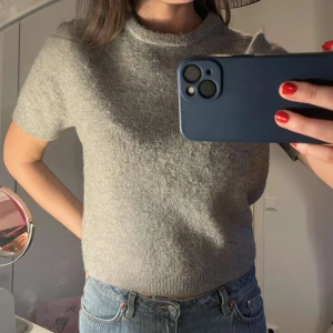 Grå kortärmad stickad tröja  Zara - Jättefin grå kortärmad stickad tröja från Zara. Aningen nopprig! Jätteskön och passar till allt!!!❤️storlek L men modellen har S i vanliga fall