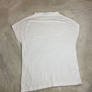 Vit t-shirt från 157 - Säljer en enkel och stilren vit t-shirt från 157. Den har korta ärmar och är tillverkad i ett mjukt material som känns skönt mot huden. Perfekt för en avslappnad look. Frakt ingår inte!!