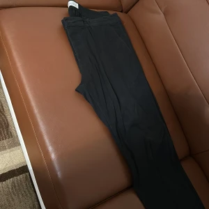 Svarta byxor från Pier One - Snygga svarta byxor från Pier One i storlek 38. De har en klassisk design med hällor för bälte och en stilren look. Perfekta för en elegant och stilren outfit.