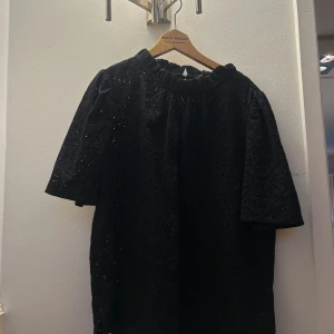 Svart blus från Cappuccini!! - Söt svart blus från Cappuccini med vackra spetsdetaljer och korta ärmar. Blusen har en rund hals och en diskret knäppning i nacken. Möjligtvis använd någon enstaka gång. Storlek 40 men super snygg lite oversized blus på mig som har XS! 🙏🏼💕