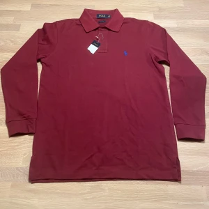 Vinröd pikétröja från Polo Ralph Lauren - Säljer en vinröd pikétröja från Polo Ralph Lauren i storlek M. Den är helt oanvänd med prislapp kvar. 