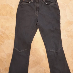 Jeans, fransar, nitar. Vintage - Snygga jeans med fransade kanter nedtill och dekorativa små nitar vid midjan och på knäna. Bootcut. De är från tidigt 2000-tal och har inte använts sen dess. VINTAGE! De är i en mörkgråblå. Kommer från H&Ms gamla collection HENNES.