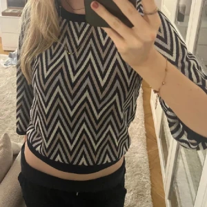 Neo noir mönstrad tröja - Säljer en snygg svartvit tröja med zigzag-mönster. Tröjan har trekvartsärmar och en rund halsringning. Perfekt för en trendig look!
