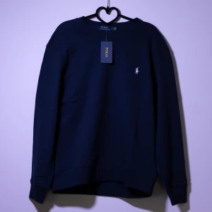 Ralph Lauren Sweatshirt - Helt ny Ralph Lauren sweatshirt med det klassiska logotypbroderiet på bröstet. Tröjan har långa ärmar och en rund halsringning, perfekt för en stilren look. Finns fler storlekar i min profil, kom gärna med frågor och bud!😁