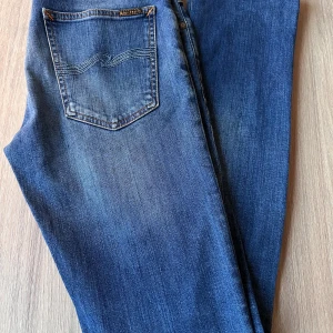 Nudie Jeans Tight Long John, storlek W30 L34 - Nudie Jeans av modell Tight Long John. Mycket fint skick. Tvätt: Broken used  En stor fördel med Nudies jeans jämfört mot Levis, Tiger of Sweden, Replay, Lee, Acne, dondup osv. är att du kan lämna in dem gratis för reparation eller uppläggning i Stockholm, Göteborg eller Malmö. På så vis förlängs livslängden rejält.   Hör av dig om du har några funderingar.