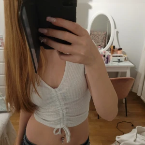 Vit ribbad linnetopp  - Snygg vit ribbad linnetopp med knytning framtill. Perfekt för varma dagar och kan enkelt matchas med olika outfits. Toppen har en stilren design och är tillverkad i ett mjukt material. Flitigt annvänd men inga defekter💕