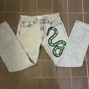 Levis 505 jeans med ormmotiv - Coola Levis 505 jeans i ljusblå denim med ett unikt ormmotiv på benet. 