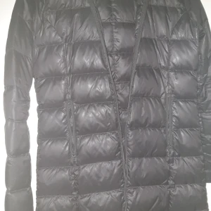 Svart dunjacka från Boomerang - Snygg svart dunjacka från Boomerang, perfekt för kyliga dagar. Jackan har en quiltad design med dragkedjor framtill och långa ärmar. En stilren och funktionell jacka för vintern.