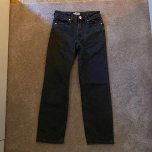 Svarta jeans från H&M - Snygga svarta jeans från H&M i en klassisk straight fit. De har en medel midja och femficksdesign med knapp och dragkedja framtill. Perfekta för en stilren look. Nästan aldrig använda. I stl 32, de är lite kortare benen💓