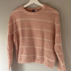 Rosa stickad tröja från H&M - Mysig rosa stickad tröja från H&M med vita ränder. Tröjan har långa ärmar och en rund halsringning. Perfekt för kyligare dagar.