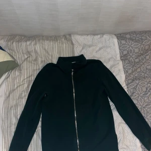 Mörkgrön tröja med dragkedja från Weekday - Säljer en stilren mörkgrön tröja från Weekday med dragkedja framtill. Tröjan har en klassisk krage och långa ärmar. Använt den 3 gånger och den är i mycket bra skick. Öppen för prisförslag.