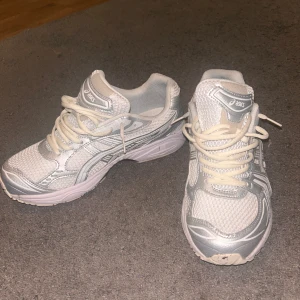 Asics gel - Snygga vita Asics gel med en sportig design. Skorna har snörning och en bekväm sula, perfekt för träning eller vardagsbruk. Tillverkade i syntetmaterial med meshdetaljer för extra andningsförmåga.