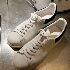  Alexander McQueen vita - Vita sneakers med svart mocca på hålen från Alexander mqueen. Sparsamt använda men lätta spår av användning så 8/10. Storlek 45 men passar även 44. Nypris ungefär 6500kr. Skickar med box och allt og.