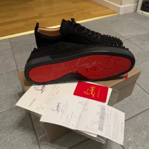 Svarta sneakers från Louboutin - Snygga svarta sneakers från Louboutin med nitar på ovansidan och den ikoniska röda sulan. Har används 1 gång 