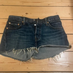 Jeansshorts från Levi's - Snygga jeansshorts från Levi's med fransiga kanter och klassisk femficksdesign. Perfekta för en avslappnad stil. De har en knappgylf och är i en mörkblå tvätt. Waist 29 (m, oversized s)