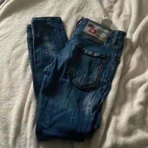 Blå jeans från Dsquared2 - Snygga blå jeans från Dsquared2 med slitna detaljer och en cool tvätt. De har en knappgylf och klassiska fem fickor. Perfekta för en avslappnad stil med en touch av edge.
