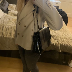 Svart axelväska  - Snygg svart axelväska i skinn med kedjedetaljer på axelremmen. Perfekt för en stilren look och rymmer allt du behöver för dagen. 🩷