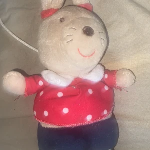 Gossedjur  - En söt mjukisdocka klädd i en röd prickig tröja och mörkblå byxor. Dockan har långa öron med röda detaljer och ett glatt ansikte. Perfekt som en mysig leksak eller dekoration.Perfekt för Barn! ❤️