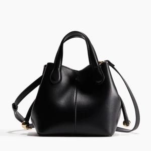 Svart handväska med axelrem - Snygg svart handväska i skinn med justerbar axelrem och guldfärgade detaljer. Väskan har en stilren design med två handtag och en rymlig insida. Perfekt för att bära med sig det viktigaste med stil. Från h&m, helt ny med prislapp kvar💗