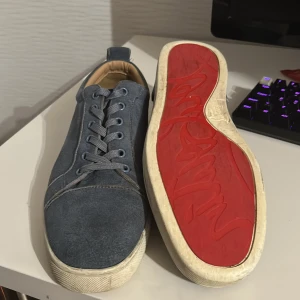 Blå sneakers med röd sula(loubs) - Snygga blå sneakers med en iögonfallande röd sula. Skorna har snörning och en stilren design som passar perfekt för en avslappnad look.
