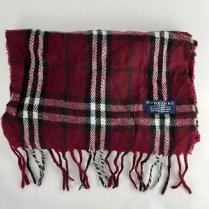 Säljer en superfin rutig halsduk från Burberry i 100% kashmir. Den är röd med inslag av svart, vit och grön, vilket ger den en klassisk look. Perfekt för att hålla sig varm under kyliga dagar. Den har fransar i ändarna som ger en extra touch av stil. Endast kemtvätt.