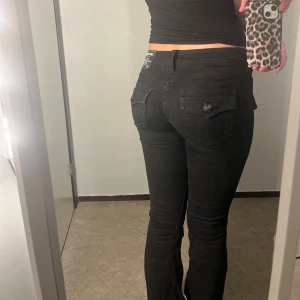 Svarta lågmidjade flare jeans från True Religion - Säljer ett par svarta lågmidjade flare jeans från True Religion, modell Joey. De har en snygg flare passform och knappar på fickorna, super snygga!!!(ny pris 1200kr) skriv gärna om du vill ha fler detaljer!