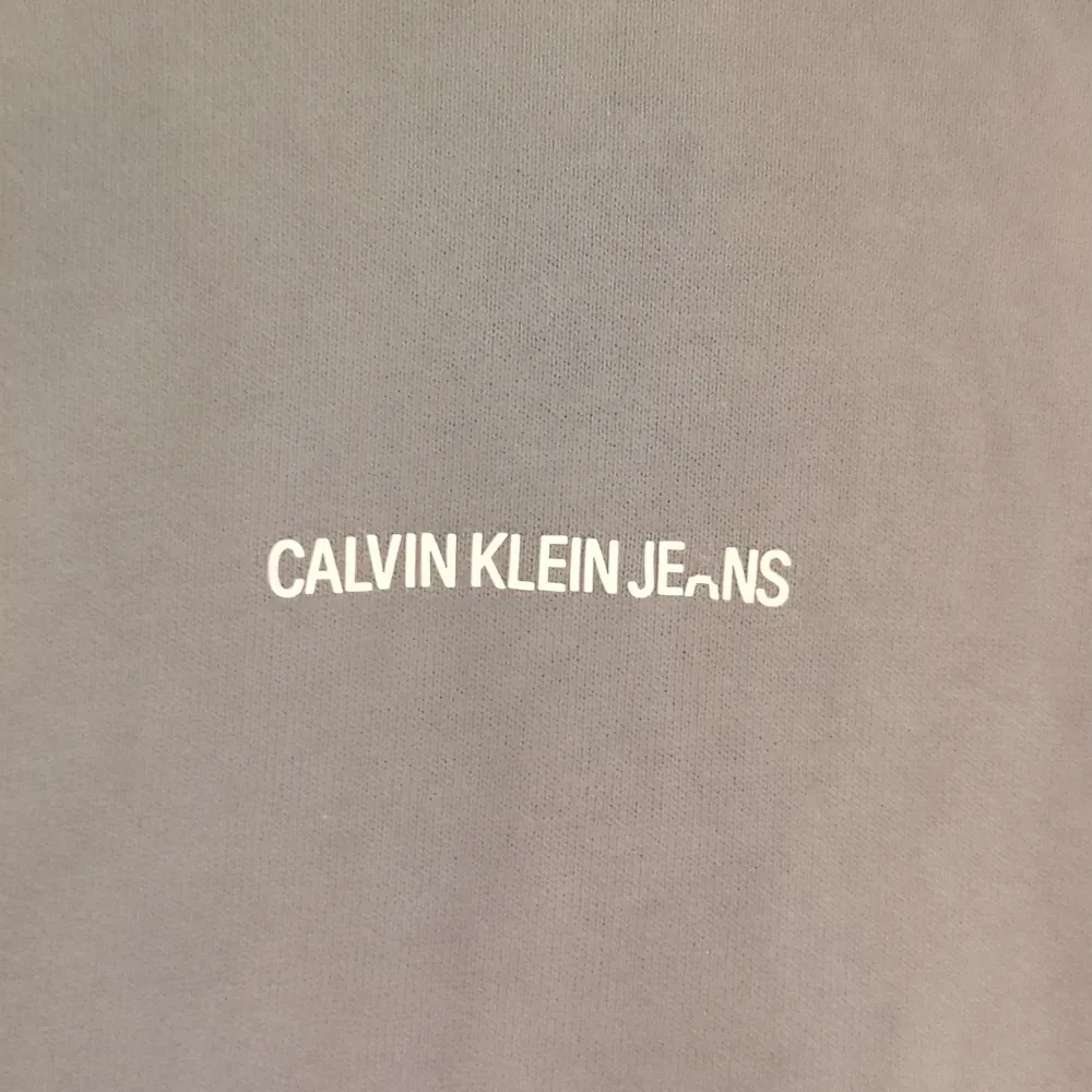 Säljer en snygg grön hoodie från Calvin Klein Jeans i storlek S. Den är i bra skick och har en klassisk design med logga på bröstet. Med en skön passform och långa ärmar. Huvan har dragsko för justering. Perfekt för en casual look! Säljs billigt på grund av att halva A är borta.. Hoodies.