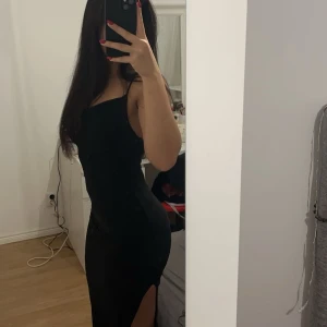 Svart långklänning - Snygg svart långklänning i tight passform. Perfekt för festliga tillfällen som nyår. Klänningen har en slits som ger en extra touch. Ankellängd, ej genomskinlig och tjockt tyg. 🖤
