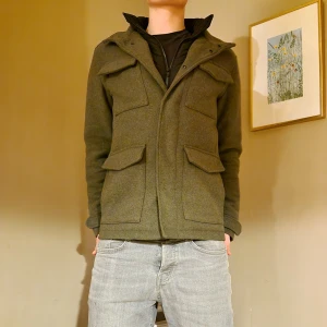 Grön jacka från Jack & Jones - Säljer en snygg grön jacka från Jack & Jones i storlek S. Jackan har en klassisk design med fyra fickor framtill, två med knappar och två sidofickor. Den är tillverkad i ett robust material som känns både slitstarkt och bekvämt. Perfekt för höst, vinter och vår!