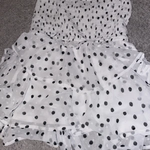 Vit prickig kjol - Superfin vit kjol med svarta prickar och volanger.  Materialet känns lätt och luftigt, vilket gör den idealisk för varma dagar🤍 