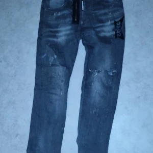 Grå jeans från DSQUARED2 - Snygga grå jeans från DSQUARED2 med en cool slitningseffekt och dragkedja. Perfekta för en trendig look. Tillverkade i Italien med högkvalitativt material.