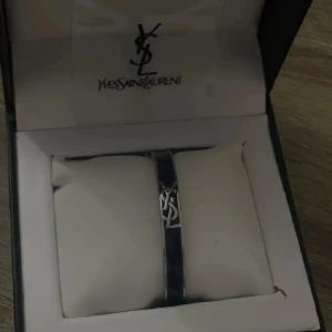 Armband från Yves Saint Laurent - Elegant armband från Yves Saint Laurent i en stilren design. Perfekt för att ge en touch av lyx till din outfit.