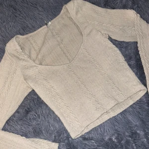 Beige stickad tröja - Säljer en superfin beige stickad tröja med v-ringning. Den har långa ärmar och ett snyggt kabelstickat mönster. Perfekt för höst och vinter, både mysig och stilren. 