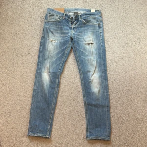 Dondup George  - Säljer ett par snygga blå jeans från Dondup i storlek 32. De har en cool slitning på framsidan och en knappgylf. Perfekta för en avslappnad stil. Passar bra till både vardag och fest! Säljer på grund av att de är för små.
