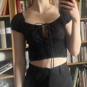 Svart croppad milkmaid topp från Motel - Svart croppad topp från Motel med korta ärmar och knytning framtill i milkmaid stil. Använd ett fåtal gånger och i perfekt skick 