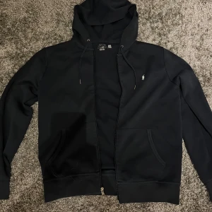 Svart hoodie från Ralph Lauren - Säljer en stilren mörkblå hoodie från Ralph Lauren med dragkedja och justerbar huva. Den är i nytt skick, använd 5-7 gånger. (Ny pris 2200kr)