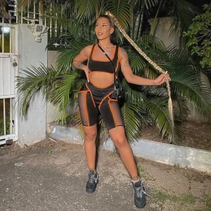 Svart och orange träningsset - Snyggt träningsset i svart med orange detaljer. Setet består av en ärmlös topp och matchande shorts med kontrasterande sömmar. Perfekt för träning eller en sportig look. Passar S och M.