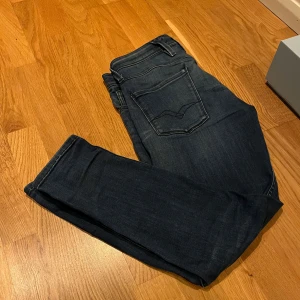 Mörkblå jeans från Replay - Snygga mörkblå jeans från Replay med klassisk femficksdesign och knappgylf. Perfekta för en avslappnad stil med en touch av elegans.