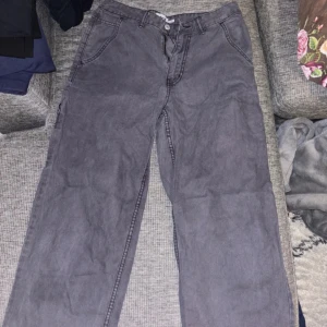 Gråa jeansbyxor - Säljer ett par gråa jeans med en snygg passform. Byxorna har en klassisk design med knapp och dragkedja framtill. Perfekta för en avslappnad stil.