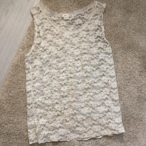 Vit spetslinne - Säljer ett superfint vitt spetslinne i mycket bra skick. Det är ärmlöst och perfekt att h under tröjor. Passar både till vardags och festliga tillfällen.