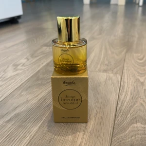 Säljer min parfym då jag inte  använder den helt ny 🥰 - Elegant Eau de Parfum från Ipande i en stilren guldfärgad flaska med matchande förpackning. Doften heter 'Things Become Beautiful' och ger en lyxig känsla. Perfekt för den som vill ha en sofistikerad och iögonfallande doft.