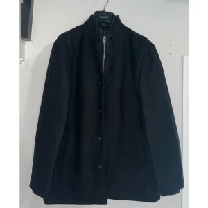 Svart rock från Jack & Jones - Säljer pga att vi tog fel storlek, använd en gång. Nypris 1599kr. Rocken stängs med både dragkedja och knappar. Perfekt för kyligare dagar och funkar som en vinterjacka. (Liten i storleken)