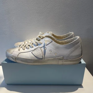 Vita sneakers från Philippe Model - Säljer ett par vita sneakers från Philippe Model i bra skick. De har en snygg och stilren design med snörning och en bekväm passform. Perfekta för både vardag och fest! Skorna kommer i originalkartong.