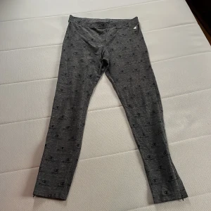 Grå leggings från Champion - Säljer ett par grå leggings från Champion i storlek L. De är i bra skick och har ett diskret mönster med Champion-loggan över hela tyget. Perfekta för en avslappnad dag eller träning. Superbekväma och stilrena!