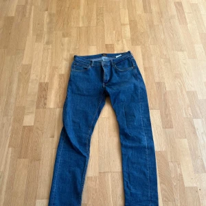 Blå jeans från Lee - Säljer ett par klassiska blå jeans från Lee i bra skick. De har en normal passform och är perfekta för både vardag och fest. Jeansen har en midwaist och är tillverkade i ett slitstarkt denimtyg. Perfekta för höst och vår!