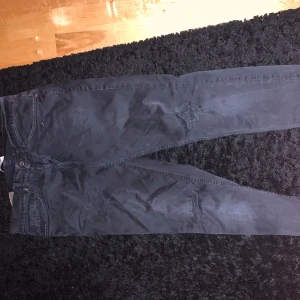 Svarta jeans från Dondup - Säljer ett par svarta jeans från Dondup i bra skick. De har en snygg, sliten look med detaljerade slitningar på framsidan. Jeansen är tillverkade i Italien och har en klassisk 5 fick design priset är inte hugget i sten