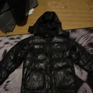 Svart dunjacka från Nike - Säljer en svart dunjacka från Nike i mycket bra skick. Jackan är perfekt för vintern med sin pufferstil och långa ärmar. Den har en dragkedja framtill och en huva för extra skydd mot kylan. Nike-loggan syns både fram och bak. Perfekt för kalla dagar! 🖤 pris kan diskuteras