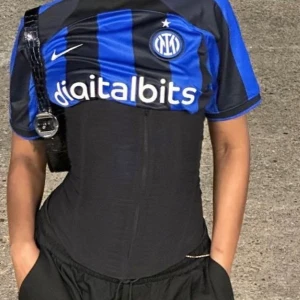 Blå och svart randig fotbollströja från Nike - Snygg fotbollströja från Nike i blått och svart med ränder. Tröjan har korta ärmar och klubbmärke på bröstet. Perfekt för fotbollsfans som vill visa sitt stöd.