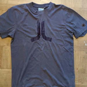 Grå t-shirt från WeSC - Snygg grå t-shirt från WeSC med ett diskret tryck på bröstet. Den har korta ärmar och en klassisk rund halsringning. Perfekt för en avslappnad stil.