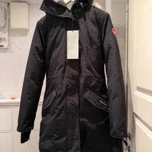 Svart parkajacka från Canada Goose - Säljer en svart jacka från Canada Goose i modellen rossclair. Ljuset på bild 3 blev lite konstigt, det är inget smuts. Jag kan skicka fler bilder vid intresse. 